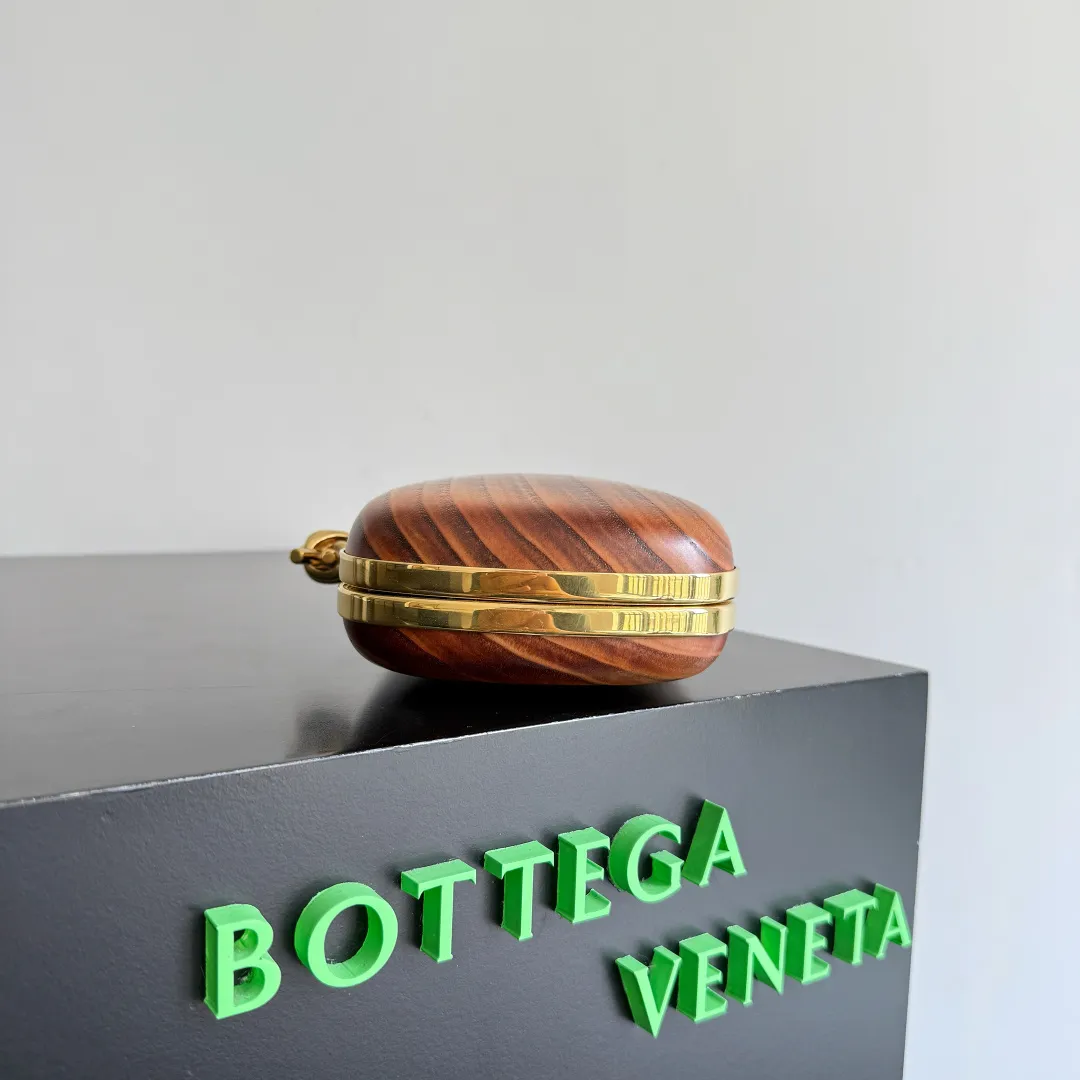 Batch 2720 BOTTEGA VENETA2025 new kont evening bag When the natural texture of wood meets the brass edge, the BV evening bag becomes a work of art in the fashion world. Every wood grain is a mark of time, delicate and unique. The brass metal buckle is embellished like stars, and opening it is full of ritual. It is the focus of the dinner party, and can easily store your exquisite small things. The warmth of wood and the cold and cool collision of metal tell the niche light luxury style in every gesture, allowing you to shine with a unique attitude in every feast. Style number: 804292 (717622) Color: maroon Size: 20.5*6*12.5cm